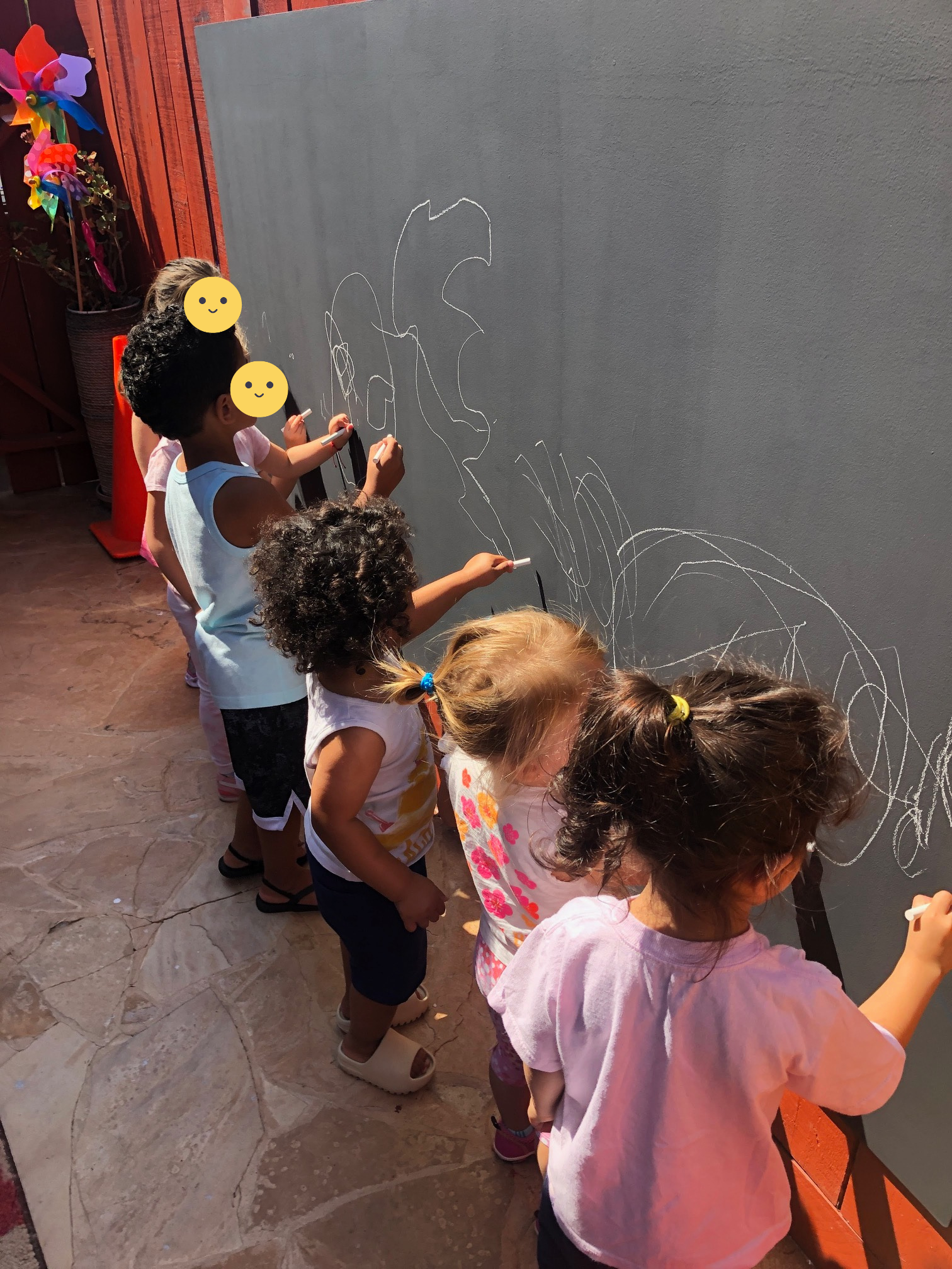 Children outside drawing on a blackboard.